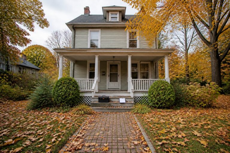 A two-story white house with a front porch and autumn leaves on the lawn, Selling a House As-Is in New Rochelle
